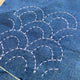 Blue fabric with white embroidery patterns on a wooden surface