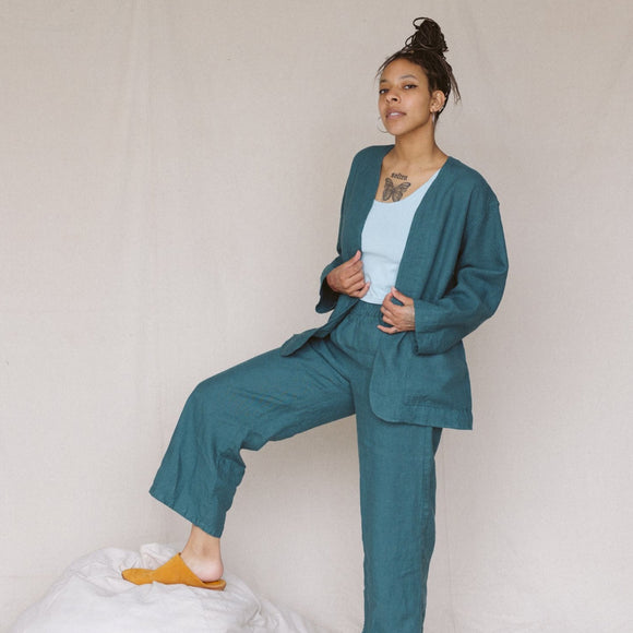 woman looking at camera wearing teal linen jacket and teal linen pants