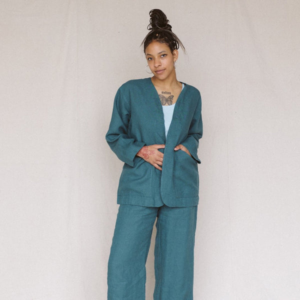 woman looking at camera wearing teal linen jacket and one hand in the jacket pocket