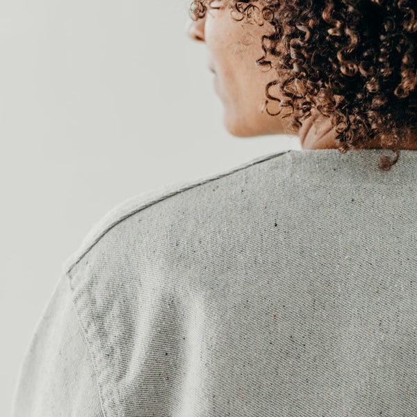 cropped image of the back of a woman's shoulder showing the seams of the denim artist jacket