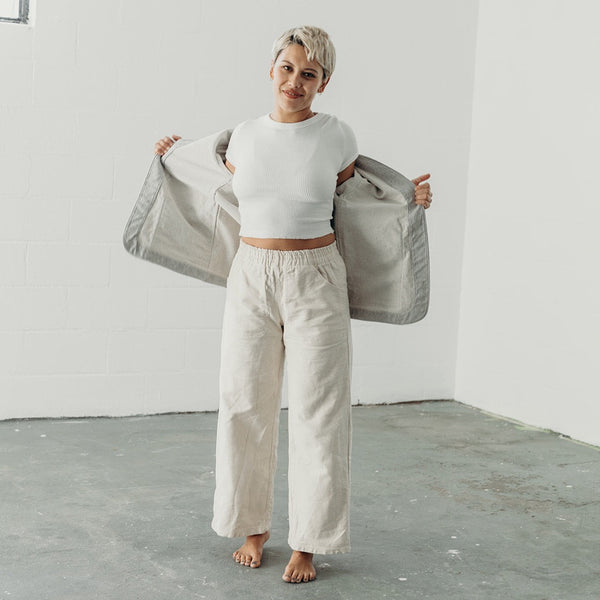 woman with frosted blond hair wearing the denim artist jacket in a motion of taking it off so you can see the inside of the jacket