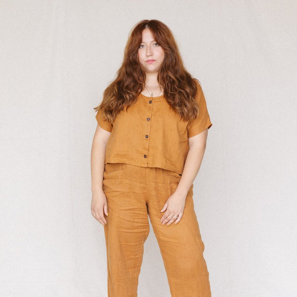 woman with auburn hair wearing rust colored linen crop top with buttons on front