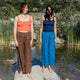 Two women standing on rocks by a body of water with mountains in the background