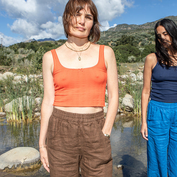Two women standing by a body of water with mountains in the background