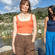 Two women standing by a body of water with mountains in the background