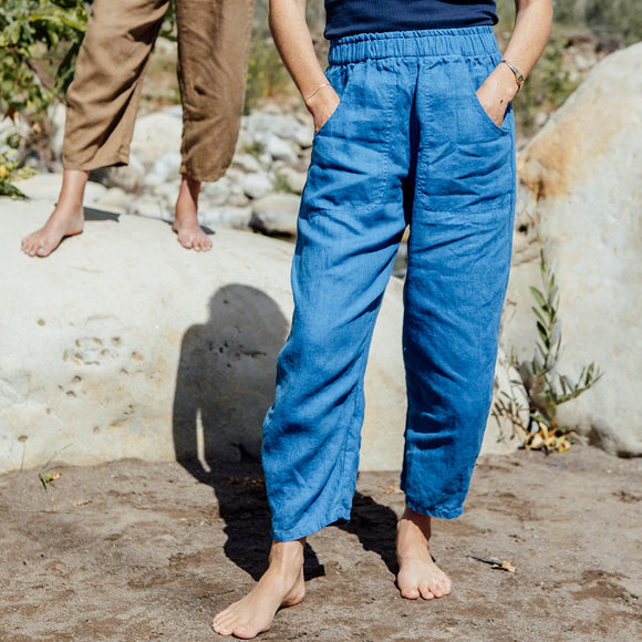 Two people wearing blue and brown pants standing outdoors with a natural background.