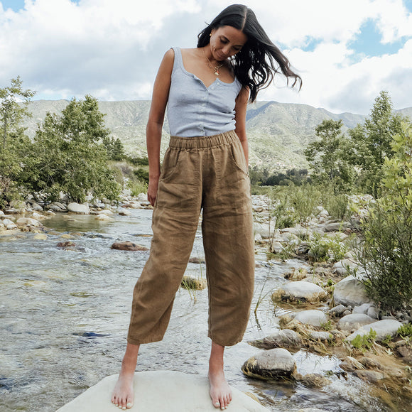 Woman standing on a rock by a river with mountains in the background