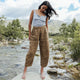 Woman standing on a rock by a river with mountains in the background