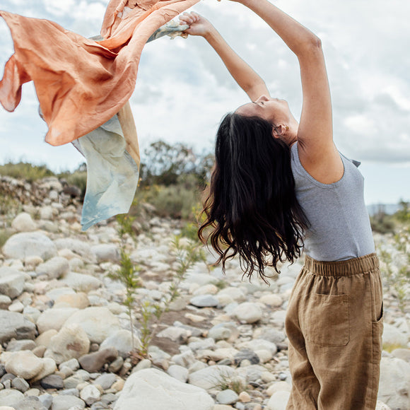 Woman stretching with a piece of fabric outdoors on a rocky path
