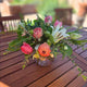 Floral arrangement on a wooden table with a blurred garden background