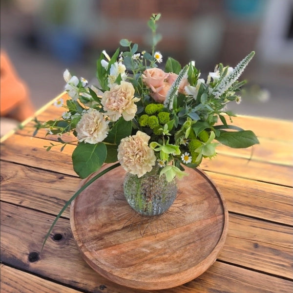Bouquet of flowers in a vase on a wooden table outdoors
