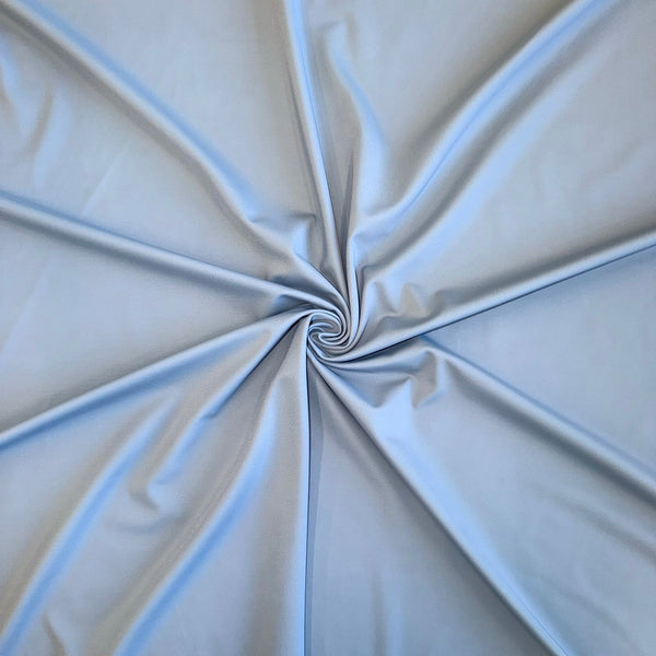 Light blue fabric draped in a spiral pattern, showing its smooth texture and soft folds.