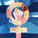 A square textile art piece featuring a feminist symbol made from patchwork fabrics, including shades of blue, pink, yellow, and brown, laid flat on a wooden floor.