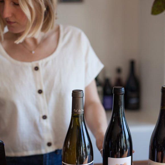 cropped image of a woman in a wine shop with wine bottles in front of her wearing a natural hemp crop top with buttons on the front