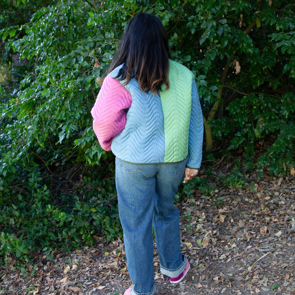 back view of woman wearing multicolored cropped quilted coat and jeans