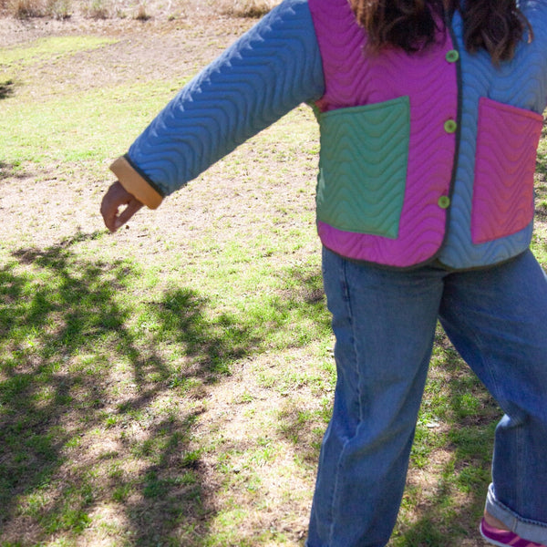 cropped image of woman moving with her arm out wearing multicolored cropped quilted coat