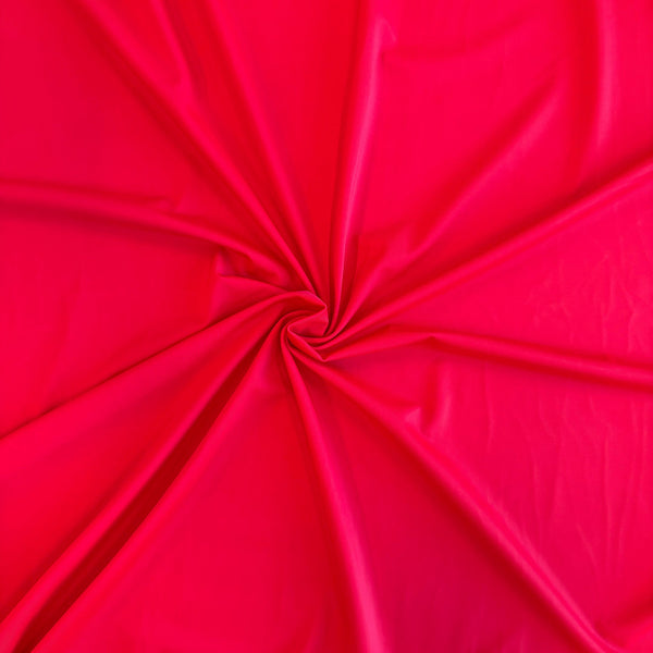 Bright red fabric draped in a spiral pattern, showing a smooth texture and glossy sheen.