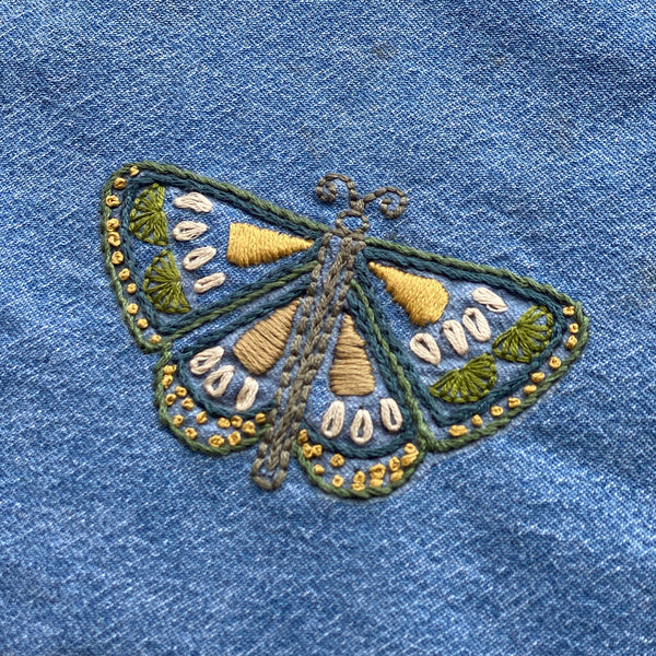 Embroidered butterfly design on a denim fabric background