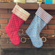 Two patterned stockings hanging on a brick fireplace.