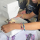 Person using a sewing machine with colorful fabric designs on paper in the foreground