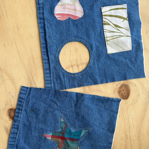 Blue denim fabric with various patches including a heart, circle, and star on a wooden surface.