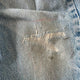 Close-up of a worn denim fabric with visible distressing and mending.