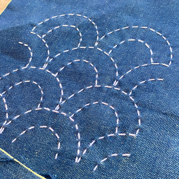 Blue fabric with white embroidery patterns on a wooden surface