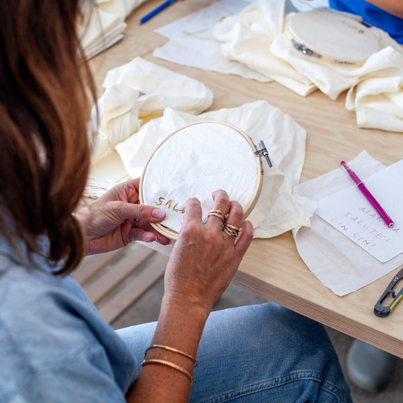 Person working on an embroidery project at a table with materials and tools.