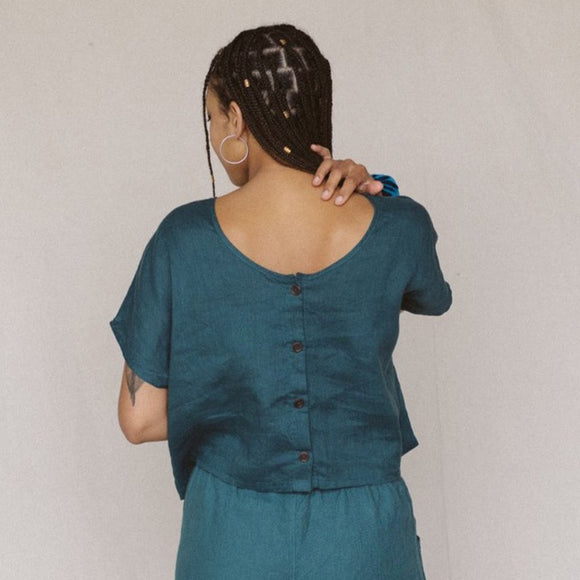 back view of a woman wearing teal linen crop top with buttons in back