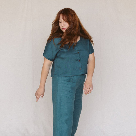 woman with auburn hair wearing a teal linen crop top with buttons in the front and matching linen pants