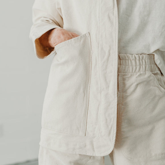 cropped photo of a cream colored canvas jacket with hand in pocket